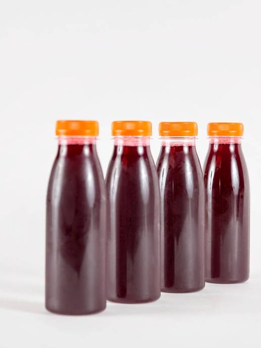 Quatre bouteilles de bissap maison, rouge profond, bouchons orange