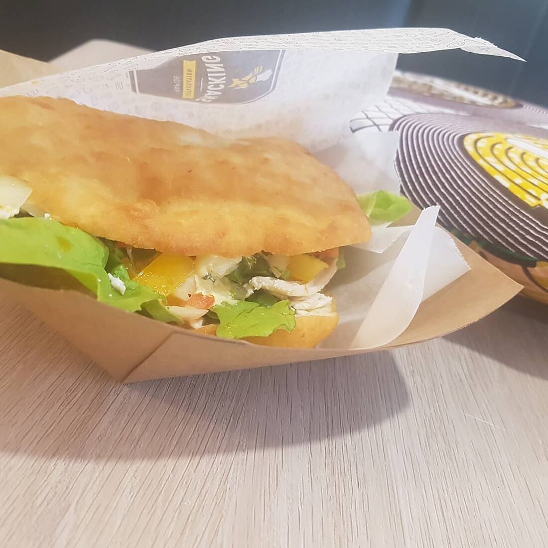 Un bokit ouvert et garni, servi dans son emballage kraft