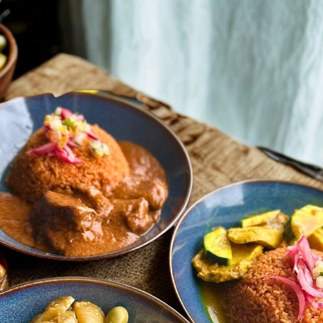 Deux assiettes de mafé avec du riz rouge et des légumes au curry
