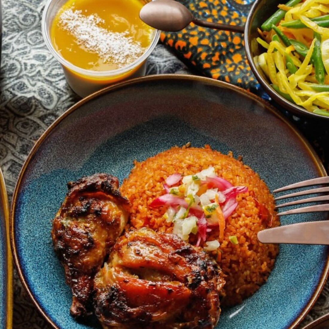 Poulet grillé caramélisé sur un lit de riz rouge, oignons marinés par-dessus