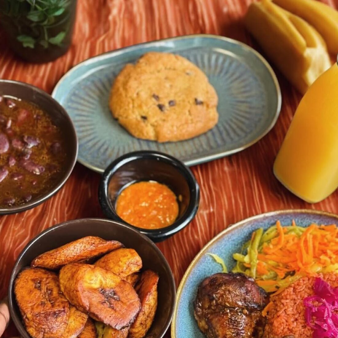 Alocco, haricots rouges, sauce piquante, crudités et poulet grillé sur une table en bois